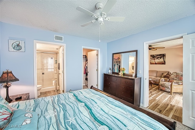 bedroom featuring a walk in closet, connected bathroom, a textured ceiling, and a closet