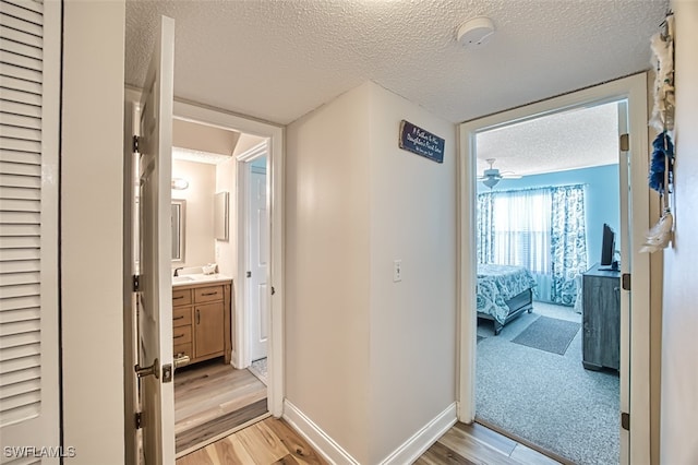 hallway with a textured ceiling and light colored carpet