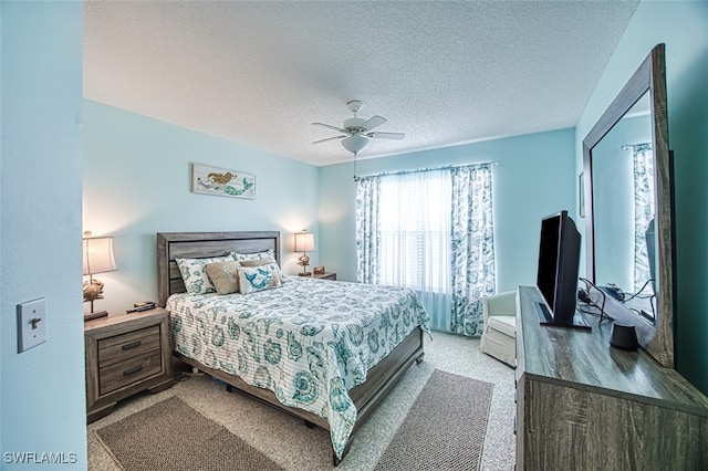 bedroom with a textured ceiling, ceiling fan, and light carpet