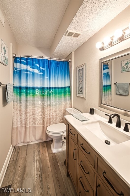 bathroom with wood-type flooring, toilet, a textured ceiling, and vanity