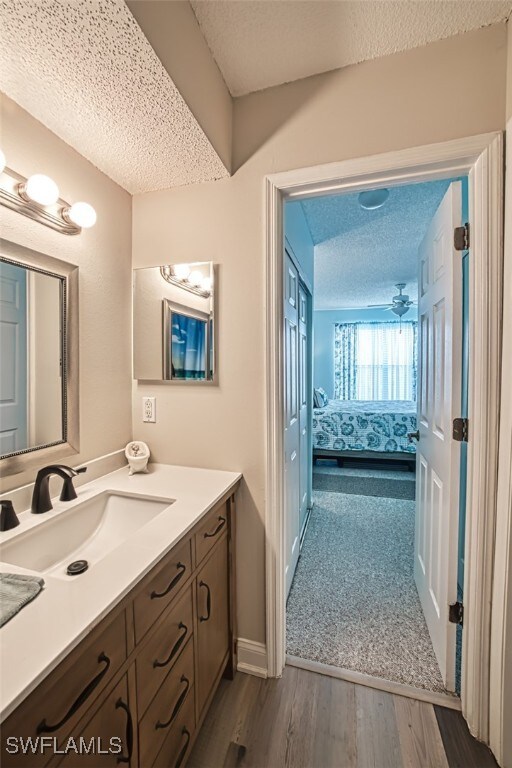 bathroom with hardwood / wood-style flooring, a textured ceiling, vanity, and ceiling fan