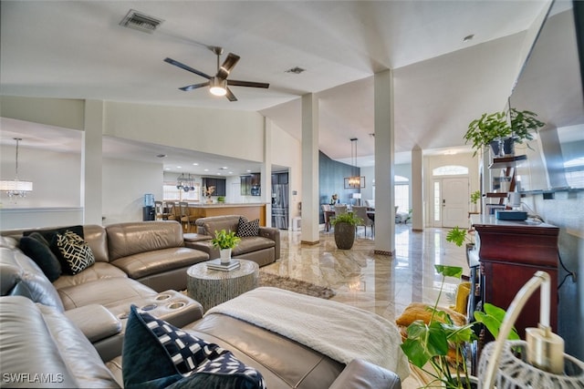 living room featuring ceiling fan with notable chandelier and vaulted ceiling