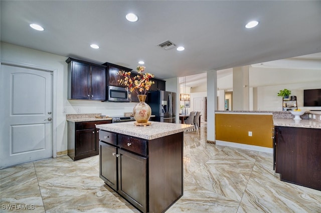 kitchen featuring appliances with stainless steel finishes, lofted ceiling, a center island, a notable chandelier, and dark brown cabinets