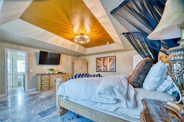 bedroom featuring a tray ceiling and ensuite bath