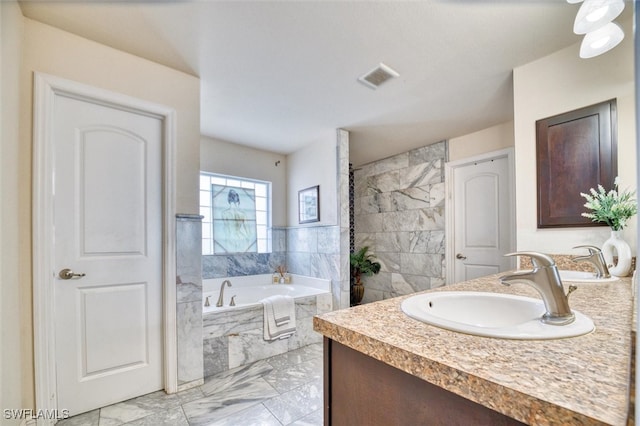 bathroom with vanity, tiled bath, and tile walls