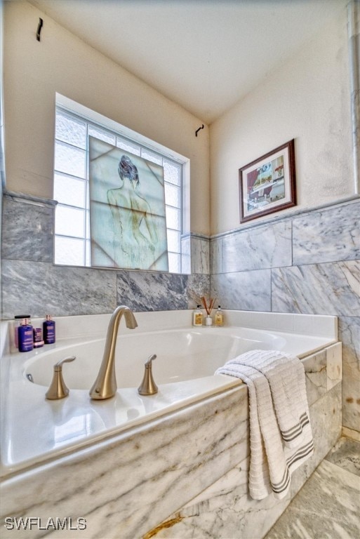 bathroom featuring a healthy amount of sunlight and tiled tub