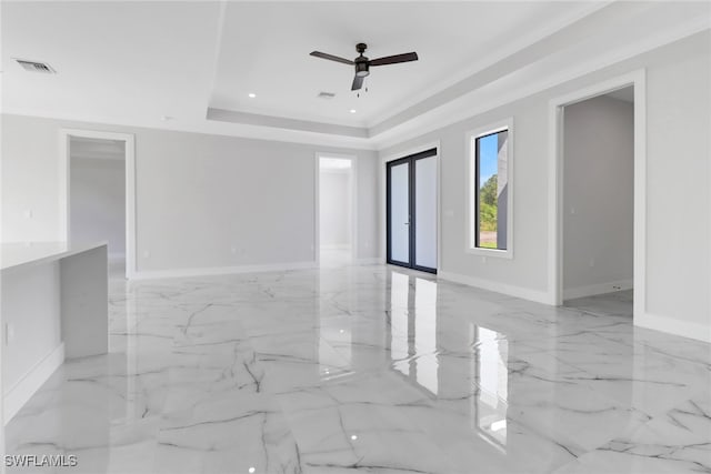 unfurnished room with light tile patterned floors, ceiling fan, and a tray ceiling