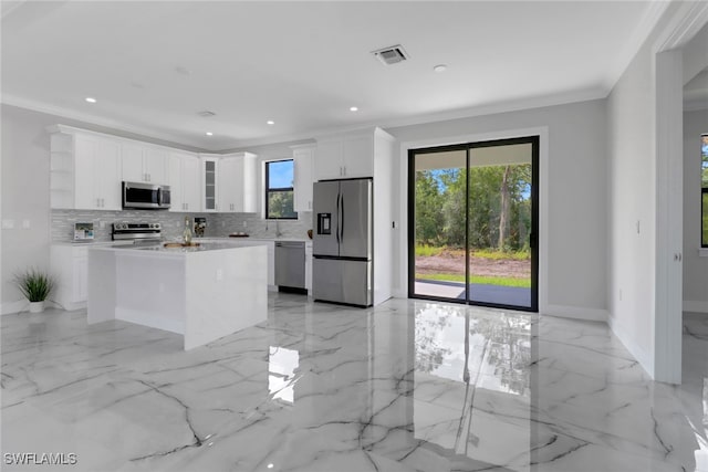 kitchen featuring backsplash, a kitchen island, white cabinetry, appliances with stainless steel finishes, and light tile patterned flooring