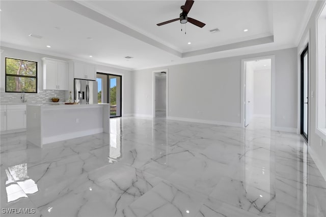 unfurnished living room with ceiling fan, a raised ceiling, light tile patterned floors, and crown molding