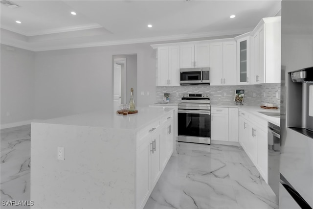 kitchen with appliances with stainless steel finishes, backsplash, a raised ceiling, white cabinets, and light tile patterned floors