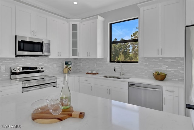 kitchen with sink, stainless steel appliances, decorative backsplash, and white cabinets