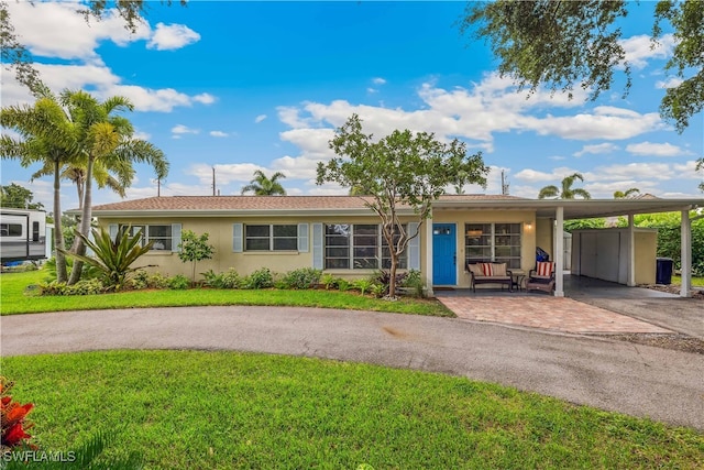 ranch-style house featuring a carport, a front yard, decorative driveway, and stucco siding