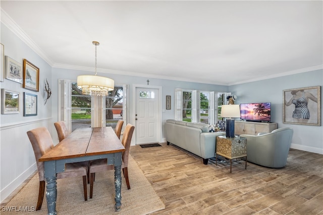 dining area with light hardwood / wood-style flooring, a chandelier, and crown molding