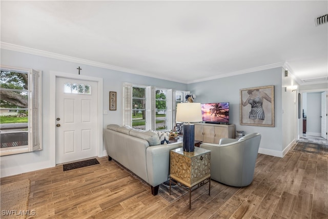 living area featuring ornamental molding, visible vents, baseboards, and wood finished floors