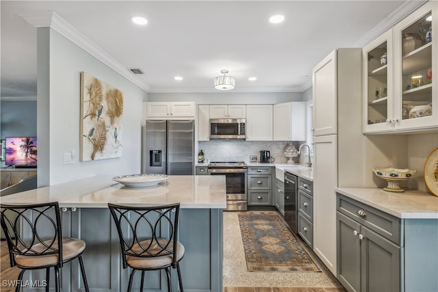 kitchen with visible vents, appliances with stainless steel finishes, gray cabinets, a kitchen bar, and crown molding