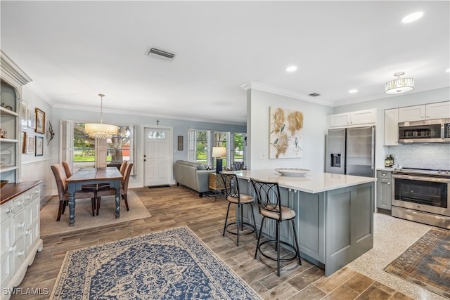 kitchen with a breakfast bar, visible vents, decorative backsplash, appliances with stainless steel finishes, and light wood-style floors