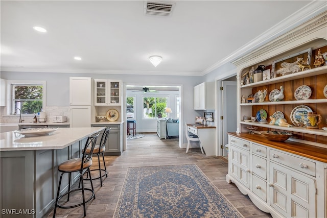 kitchen featuring visible vents, crown molding, a kitchen bar, and wood finished floors