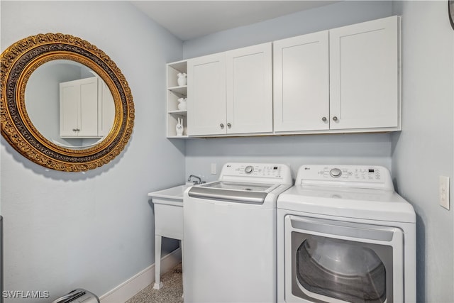 clothes washing area featuring cabinet space, washing machine and dryer, and baseboards