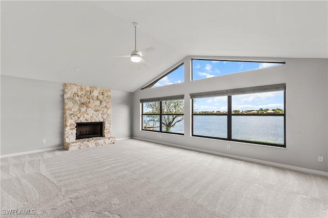 unfurnished living room featuring a fireplace, high vaulted ceiling, carpet flooring, ceiling fan, and a water view