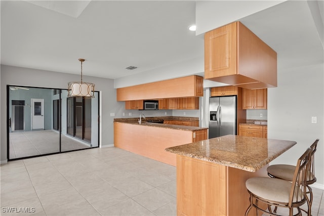 kitchen with dark stone counters, stainless steel appliances, kitchen peninsula, hanging light fixtures, and a breakfast bar