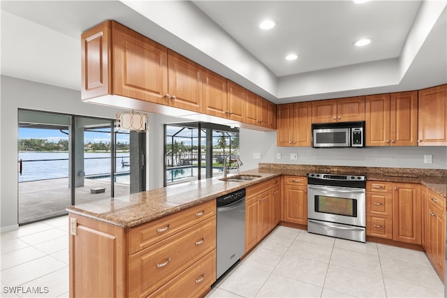 kitchen featuring appliances with stainless steel finishes, a wealth of natural light, sink, and stone counters