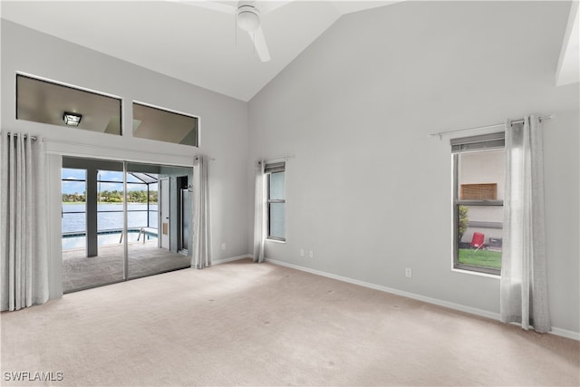 carpeted empty room with french doors, high vaulted ceiling, ceiling fan, and a water view