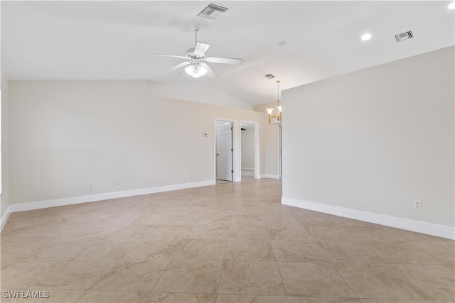 tiled empty room featuring lofted ceiling and ceiling fan with notable chandelier