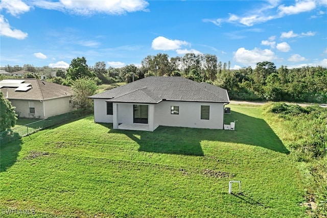 2802 63rd St W, Lehigh Acres, FL 33971 - rear view of house with a yard, stucco siding, a patio, and a shingled roof