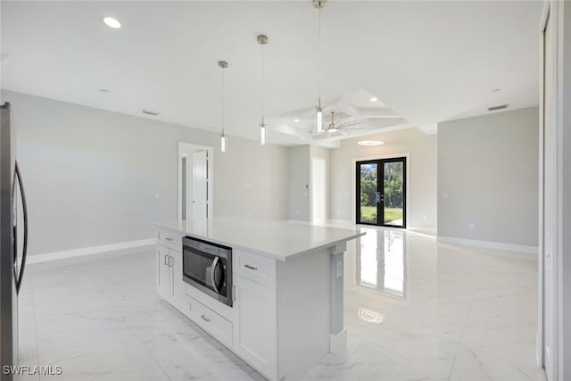 kitchen with appliances with stainless steel finishes, a kitchen island, french doors, hanging light fixtures, and white cabinetry