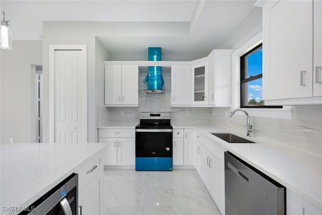 kitchen with light stone counters, appliances with stainless steel finishes, white cabinetry, pendant lighting, and sink