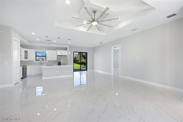 empty room with sink, a tray ceiling, and ceiling fan