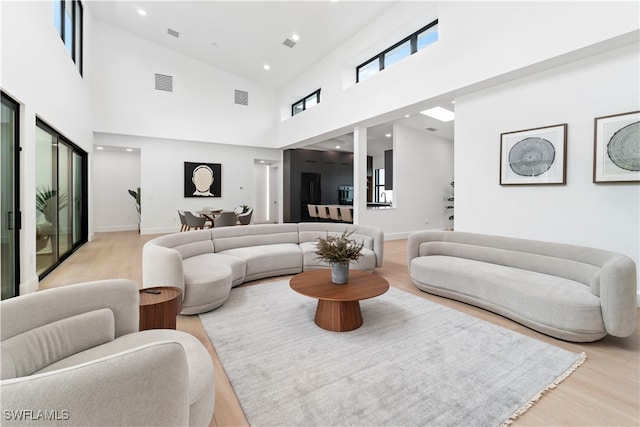 living room with light wood-type flooring and high vaulted ceiling