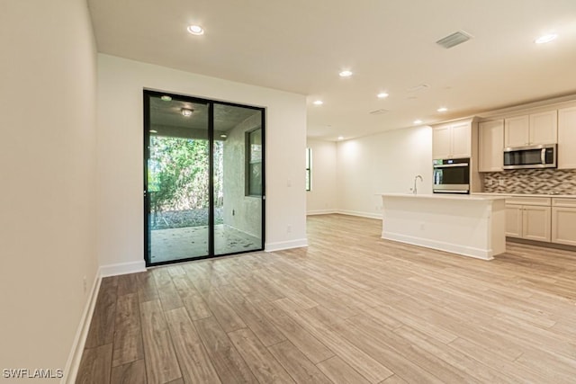 unfurnished living room with light hardwood / wood-style flooring and sink