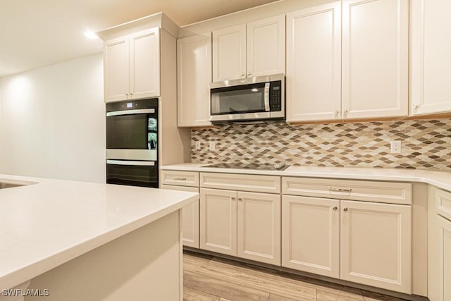 kitchen with tasteful backsplash, stainless steel appliances, sink, light hardwood / wood-style floors, and white cabinetry