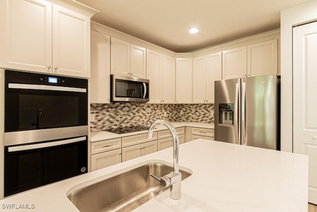 kitchen with white cabinets, backsplash, sink, and appliances with stainless steel finishes