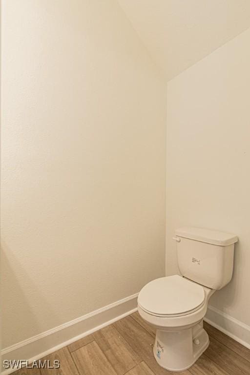 bathroom featuring wood-type flooring, toilet, and lofted ceiling