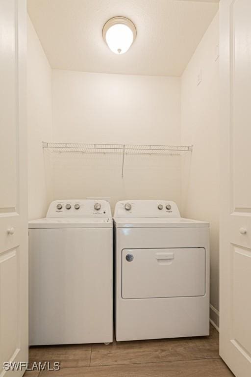 clothes washing area featuring washer and dryer and wood-type flooring