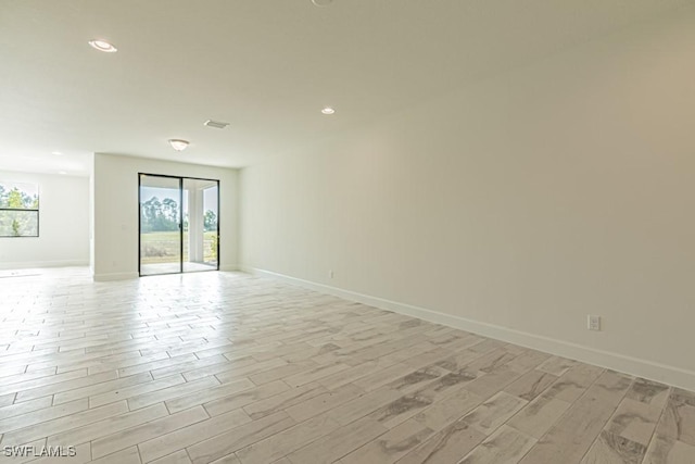 spare room featuring light hardwood / wood-style flooring and a healthy amount of sunlight