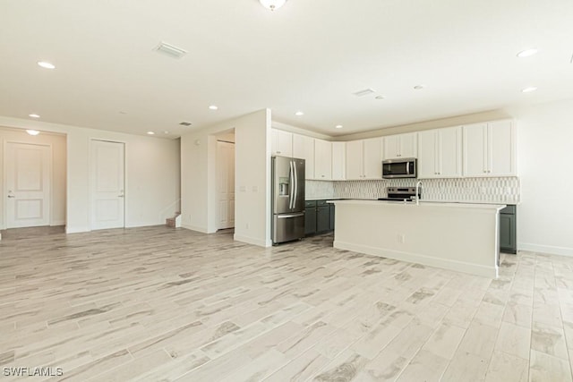 kitchen with white cabinetry, a kitchen island with sink, stainless steel appliances, and light hardwood / wood-style floors