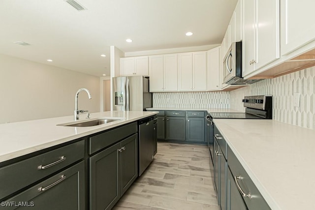 kitchen with sink, stainless steel appliances, backsplash, white cabinets, and light wood-type flooring