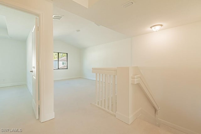 hall featuring light carpet and vaulted ceiling