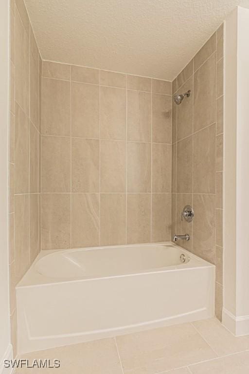 bathroom featuring tile patterned floors, tiled shower / bath combo, and a textured ceiling