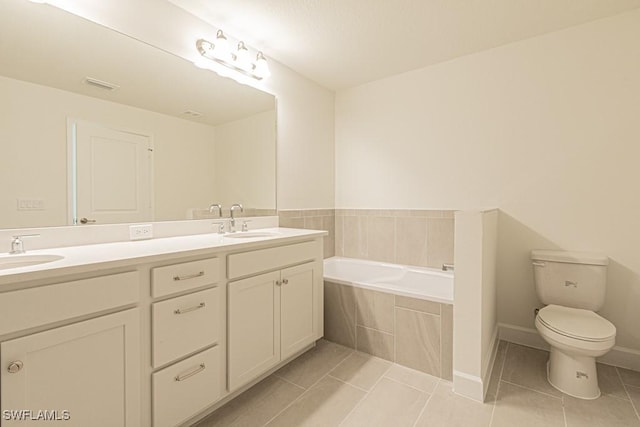 bathroom featuring tiled bath, tile patterned flooring, vanity, and toilet