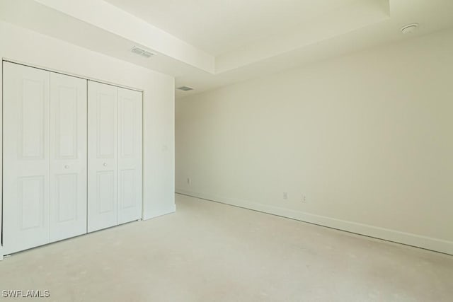 unfurnished bedroom with a tray ceiling and a closet