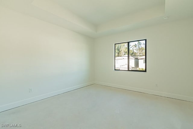 empty room with a tray ceiling and concrete floors