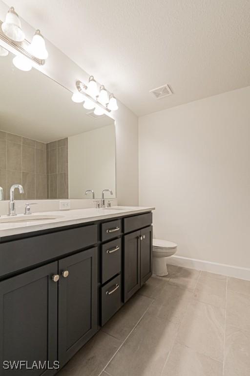 bathroom featuring tile patterned flooring, vanity, and toilet