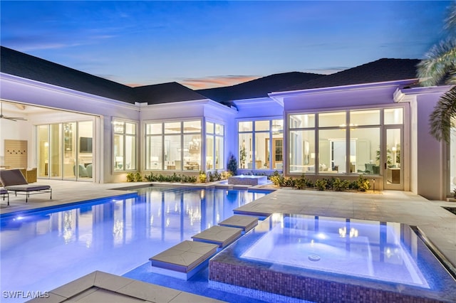 pool at dusk featuring a patio area and an in ground hot tub