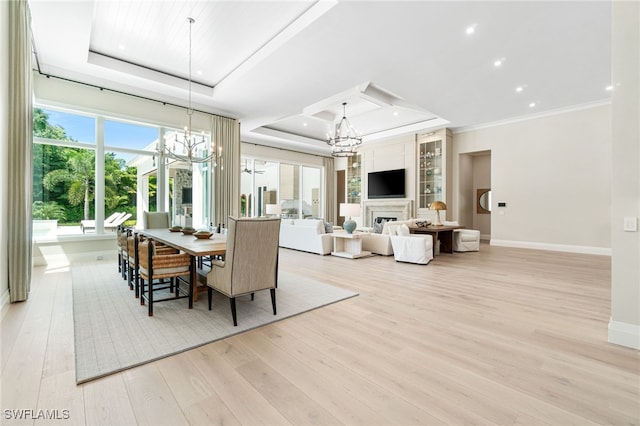 dining area with a tray ceiling, built in shelves, crown molding, and light hardwood / wood-style flooring