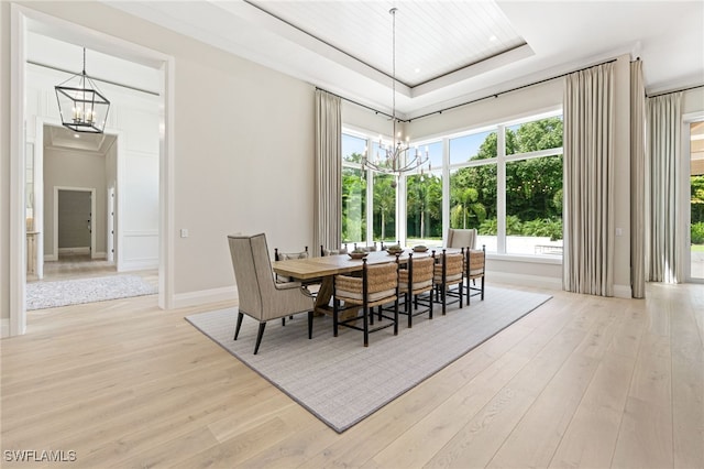 dining room featuring light hardwood / wood-style floors, a tray ceiling, and a notable chandelier