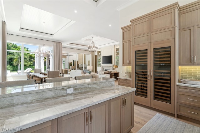 kitchen featuring a raised ceiling, tasteful backsplash, pendant lighting, and light hardwood / wood-style flooring